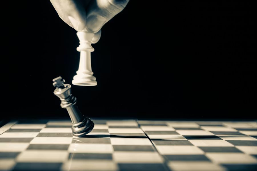 A hand moving a chess piece to checkmate the opposing king